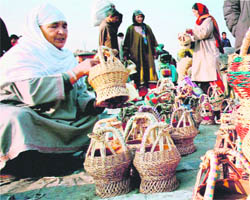 Women buy kangris from a roadside vendor in Srinagar on Tuesday. The sale of kangris has picked up during the past few days due to a drastic fall in the temperature.