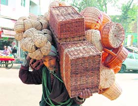 An elderly person sells handmade baskets to earn a livelihood in a busy market in Jammu. 