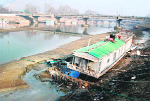 A shikara struggles to balance itself in the Jhelum as the water level in the river has receded due to the prolonged dry spell in the Kashmir valley. 