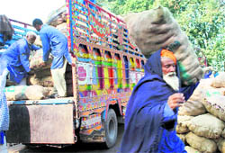 Porters unload bags of onions from a truck that arrived from Pakistan at the 