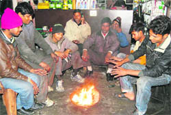 Residents gather around a bonfire to beat the chill in Dehradun on Friday