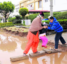 A resident helps her children reach their home with great difficulty in Sector 28, Chandigarh