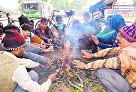 Rickshaw-pullers sit around a bonfire opposite the ISBT, Sector 43, Chandigarh