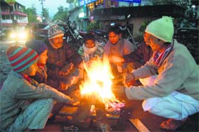 People try to warm themselves sitting around a bonfire in Dehradun