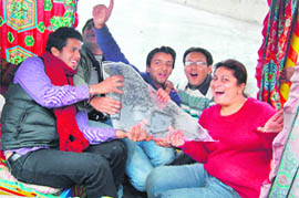 Tourists hold a sheet of ice in a shikara in the frozen Dal Lake in Srinagar 
