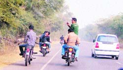 Youths shoot a video of a motorcyclist performing daredevil stunts on Ferozepur road