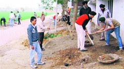 Volunteers clear brims of a road leading to Kanganwal near Ahmedgarh on Sunday.