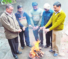 People warm themselves as the cold wave intensifies in Jammu on Monday