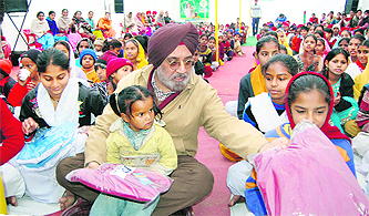 Harpal Singh, chairperson of the Nanhi Chhaan Foundation, distributes uniforms among schoolchildren at a function in Amritsar on Monday.