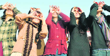 College girls look at the Sun during the solar eclipse in Haridwar 