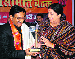 Chief Minister Ramesh Pokhriyal Nishank presents a memento to Smriti Irani in Dehradun on Tuesday