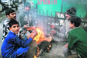 People huddle around a bonfire to keep themselves warm on a chilly day in Jammu.