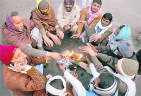 Labourers sit around a bonfire to keep themselves warm on a chilly day in Jalandhar on Tuesday. 