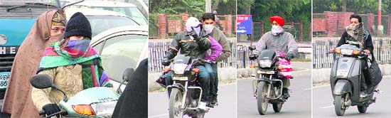Two-wheeler riders cover their faces to avoid chilly winds in Ludhiana on Tuesday.
