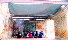Students of Government Primary School-1A, Jail Raod, sit on the floor with a tarpaulin as a roof on a chilly Tuesday afternoon.