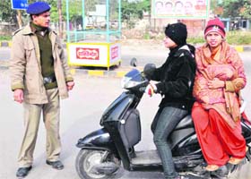 A traffic policeman stops a girl driving a scooter without helmet in Haridwar