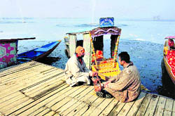 Boatmen sit near the partially frozen Dal Lake in Srinagar on Wednesday