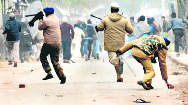 A cop picks a stone to disperse the rioting mob after the police came under attack in Burail village on Thursday.