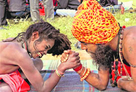 Two sadhus try their hand at arm wrestling at a temporary camp for the Gangasagar Mela 