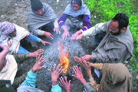 Residents huddle around a bonfire to keep themselves warm on a chilly day in Jammu.