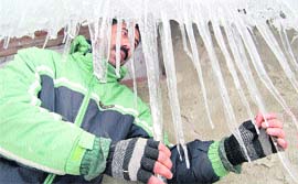 A man shows icicles hanging from the roof of a government tourist hut at Gulmarg in Baramulla district on Saturday.