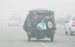 Commuters travel in an auto-rickshaw on the Ambala-Chandigarh highway on a foggy Sunday morning