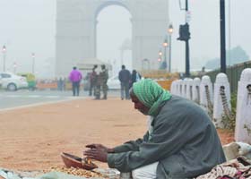 A vendor warms himself at India Gate on a foggy and cold day in New Delhi