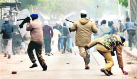 In the wake of an unyielding lathi, a policeman picks up a stone to scare away a mob protesting the death of the kidnapped child, Khushpreet, in chandigarh.