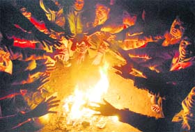 People warm themselves up around a bonfire at Panchkula on Monday evening