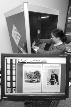Jana Passehl, a librarian at Greifswald University Library in Germany, lays a 1909 book in a robotic scanner. The monitor in the foreground shows the images it has made. The library is one of many in Germany that are converting paper books to digital images to improve offsite access to books and reduce wear on old treasures.