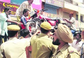 Police personnel take away a motorcycle parked wrongly on a road in Ambala