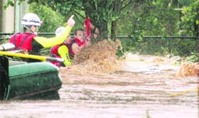 A man is rescued by emergency workers after he was stranded clinging to a tree on a flooded street in Toowoomba during a flash flood on Monday. Flash floods swept through the northeastern Australian community killing four persons.