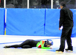 An ice skater falls after being pushed