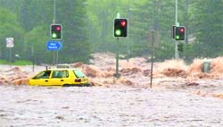A passenger in a car waves for assistance as a flash flood sweeps across an intersection in Toowoomba on Tuesday.
