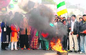Supporters of the Gorkha People's Liberation Front (GJM) raise slogans and wave flags near a burning tyre as they block the National Highway No. 55 at Panchanai village on the outskirts of Siliguri