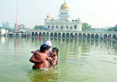 A Sikh family takes a dip in the Gurdawara Bangla Sahib sarovar in New Delhi on the occasion of Makar Sankranti on Friday. 