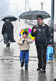 Residents walk with umbrellas during snowfall in Srinagar on Friday