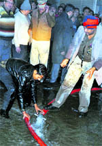 A fireman connects a hose to draw water from a tanker parked away from the narrow street
