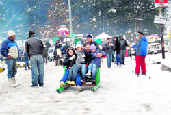 Tourists enjoy sledging on the Mall road in Manali 