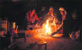 Members of a labourer family try to keep themselves warm sitting around a bonfire in their makeshift house in Karnal.