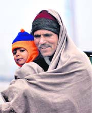 A man and his son sit on the stairs of Jammu railway station on Monday.