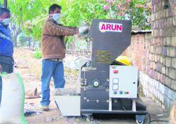 A shredder processing polythene waste for use as road surfacing material at Nurpur