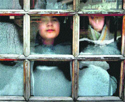 A girl looks through a misty windowpane of her house in Srinagar on Tuesday.
