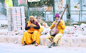 An elderly couple plays musical instruments on a roadside in Gurgaon.