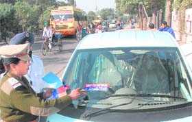 A traffic police officer pastes a sticker on the windscreen of a car for wrong parking in Jalandhar