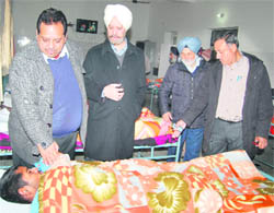 The Chief Parliamentary Secretary (Health) inquires about the health of an inmate after handing over cheque for Rs 1 lakh to Pingalwara in Jalandhar on Thursday.