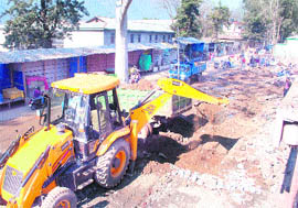 A machine at work to remove encroachments on the premises of the Paddal stadium in Mandi on Friday.