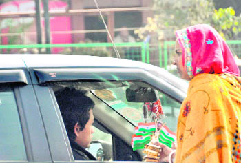 As the Republic Day approaches, a woman sells national flags at a busy intersection in Dehradun