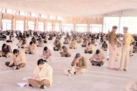 Aspirants take an exam for the posts of sub-inspector while sitting on the floor in Haridwar