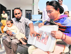Gurminderjit Kaur shows pictures of members of her family in Ludhiana on Monday.
